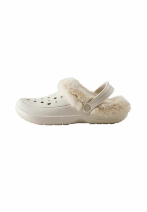 White slip-on clog with ventilation holes, a fluffy beige fur lining, and an adjustable strap at the heel.