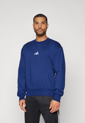 Felpa blu navy con scollatura rotonda e polsini a coste. Presenta un piccolo logo Adidas bianco sul petto. Tessuto morbido con vestibilità comoda.