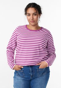 Majica dugih rukava sa prugama u naizmjeničnoj ljubičastoj i bijeloj boji, rebraste teksture, okruglog izreza, u kombinaciji s trapericama visokog struka.