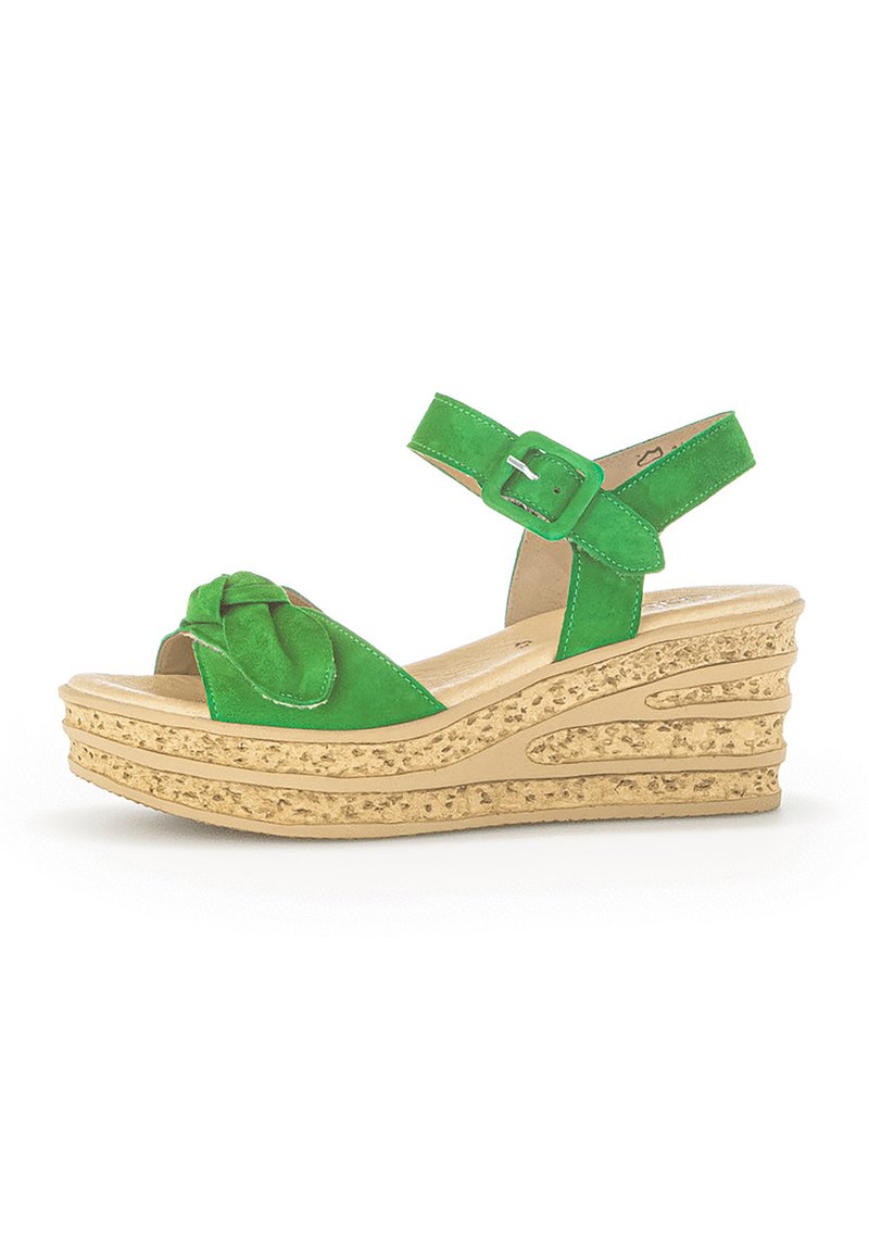 Sandales compensées en daim vert avec une bride à boucle et un design à l'avant noué, possédant une semelle beige texturée avec des rainures courbes.