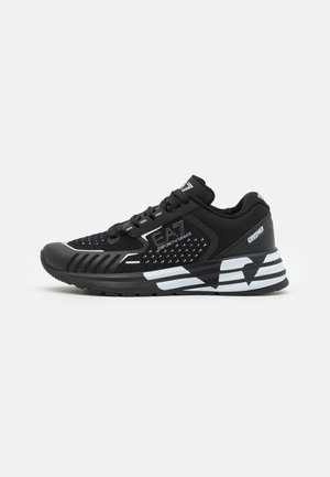 Baskets de sport noires avec semelle blanche à rayures, dessus en mesh et synthétique, marqué « EA7 Emporio Armani » et « Crusher » sur le talon.