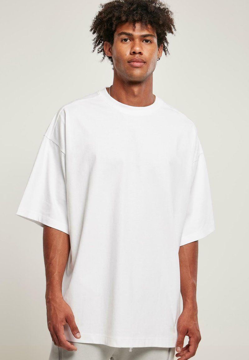 Hvid oversized bomulds T-shirt med korte ærmer, der har en rund hals og minimalt syning detaljer. Blød tekstur og afslappet pasform.