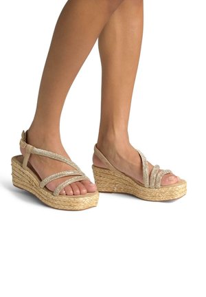 Wedge sandals featuring a beige fabric upper with metallic straps, a braided jute sole, and an open toe design.
