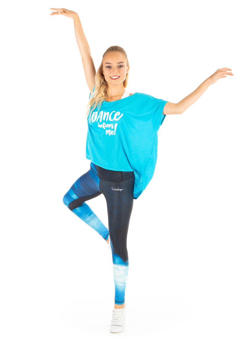 Turquoise oversized shirt met witte tekst, gecombineerd met blauwe ombre leggings. Witte sneakers maken de dansoutfit compleet.