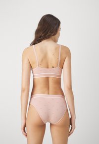 Light pink lingerie set featuring a bralette and high-waisted briefs, with thin white stripes and subtle patterned accents on the fabric.