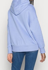 Felpa leggera blu con una vestibilità rilassata, orlo e polsini a coste, e cappuccio con cordino. Materiale morbido in misto cotone con dettagli delle cuciture minimi.
