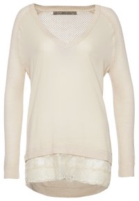 Pull beige col en V avec manches en maille et ourlet superposé orné de dentelle, fabriqué par Guess.