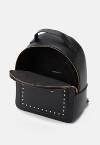 Sort læder rygsæk med et afrundet design, guldlås og hjerteformede nitter på forsiden. Rummelig indvendig med en blød foder.