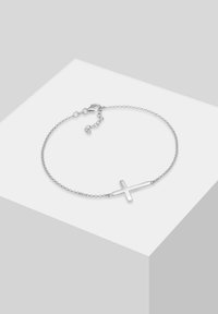 Pulsera de cadena de plata con un charm de cruz minimalista. Cuenta con un cierre de langosta y longitud ajustable con eslabones finos. Acabado liso y pulido.