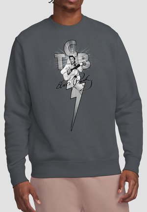 Man wearing dark gray sweatshirt with black and white graphic of Elvis Presley playing guitar, a lightning bolt, and cursive signature.