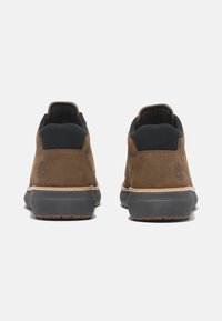 Brown leather sneakers with a suede texture, padded black collar, rubber sole, and beige stitching. Logo embossed on the heel.