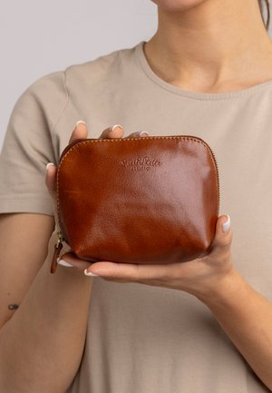 Brown leather zippered pouch with rounded shape, featuring a smooth texture and embossed brand logo on one side.