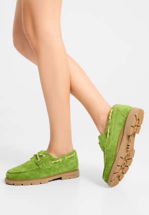 Grønne hverdags sko i ruskind med en struktureret overflade, kontrasterende beige sål og guldfarvede huller til snørebånd. Lavprofil design.