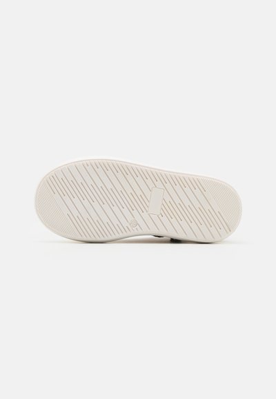 Semelle de sneaker blanche avec des crêtes texturées et un design plat. Présente un rectangle central et des marquages numérotés près du talon.