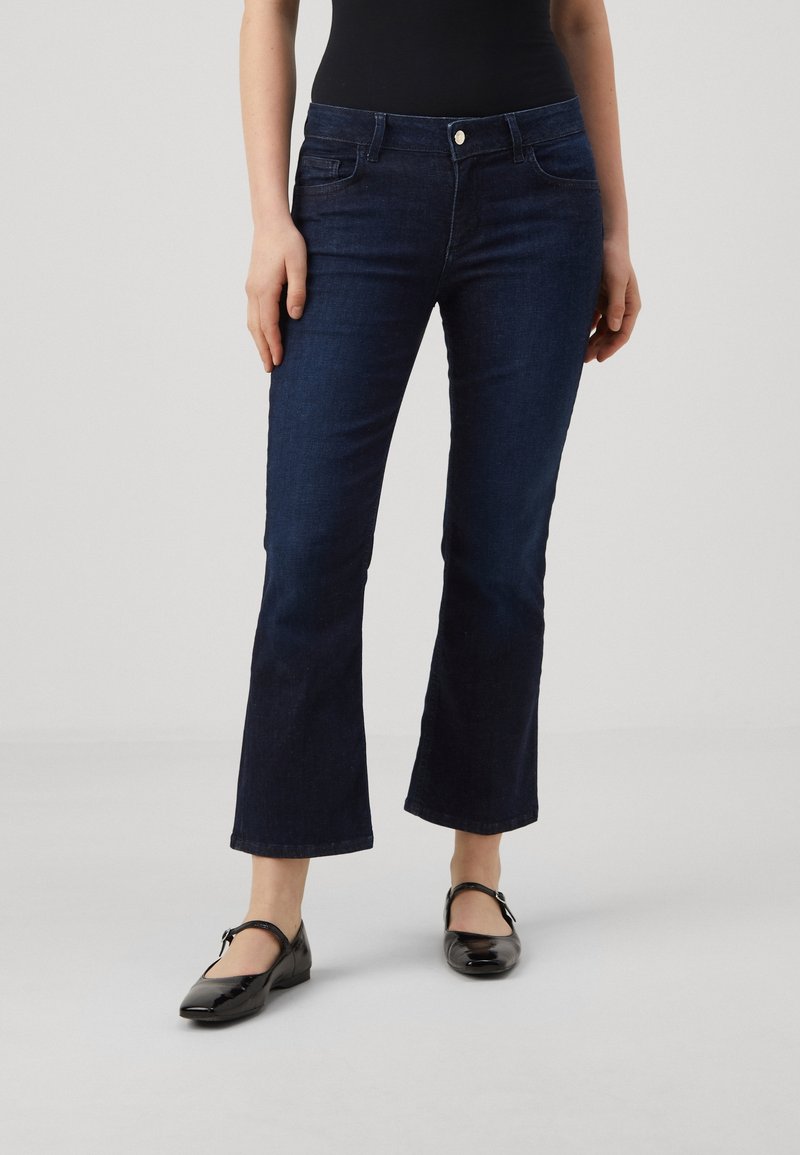 Tmavě modré rozšířené džínové kalhoty s klasickým pětikošilovým designem, vyrobené z denimového materiálu s jemnou texturou a s jedním předním knoflíkem.