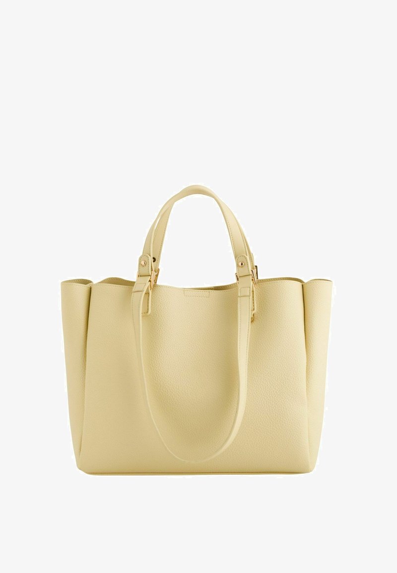 Bolso tote de cuero color crema con dos asas cortas y una correa larga extendida, con un diseño estructurado y herrajes en tono dorado.