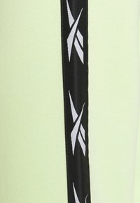 Un tissu vert clair présente une bande noire sur le côté avec des motifs abstraits blancs. La texture est lisse avec un aspect légèrement structuré.