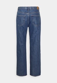 Siniset farkut suorilla lahkeilla. Ominaisuuksiin kuuluvat korkeavyötärö, kaksi takataskua ja vaaleanruskea nahkainen merkki vyötäröllä.