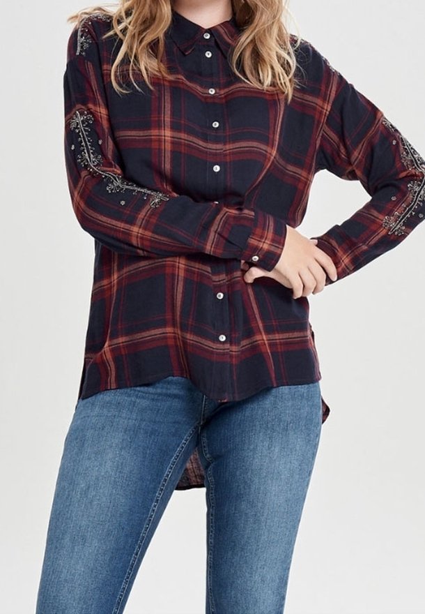 Navy plaid button-up shirt with red accents, long sleeves, and decorative embroidery on sleeves. Paired with blue denim jeans.