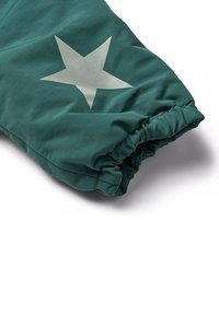 Grön isolerad jacka med mudd i ärmen och elastisk midja, med en stor silvstar design och ett texturerat tygmönster.