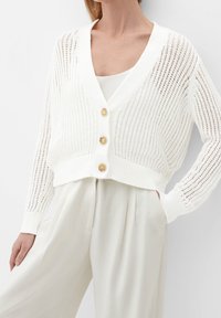 Vitt stickad cardigan med lös passform, med en djup V-ringning, tre stora gyllene knappar och en ribbad textur.