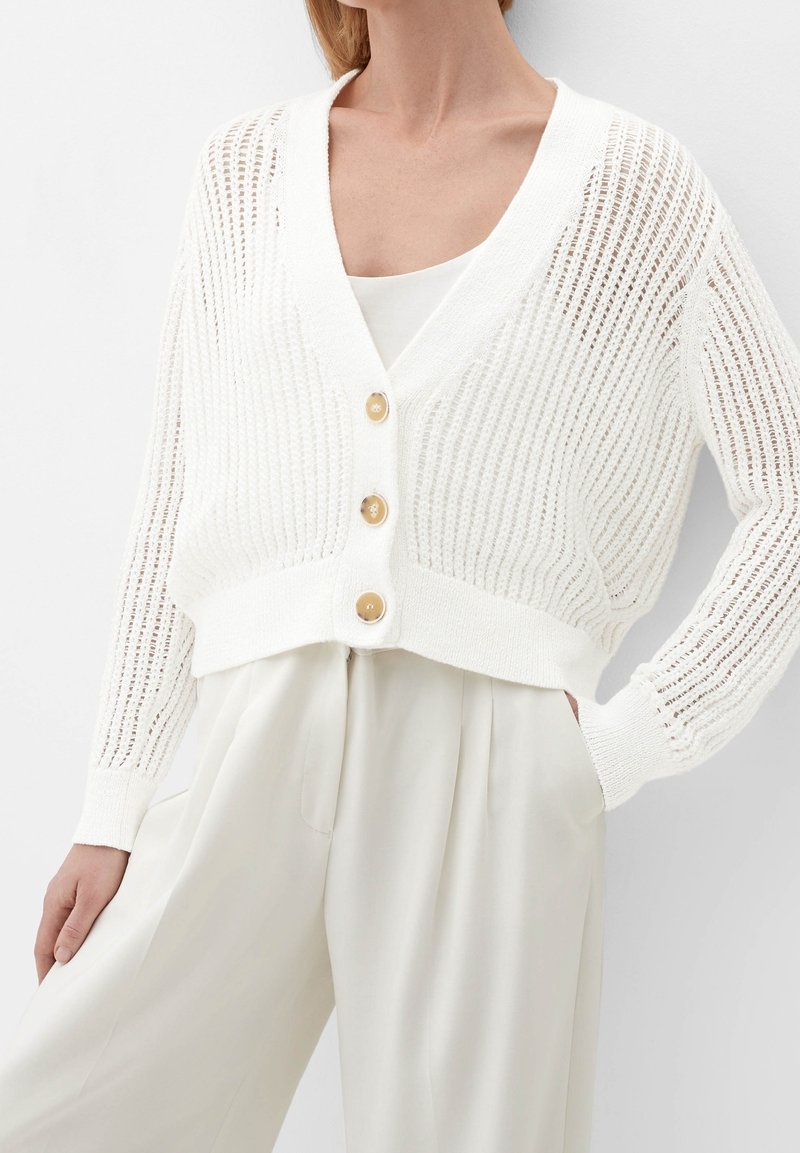 Vitt stickad cardigan med lös passform, med en djup V-ringning, tre stora gyllene knappar och en ribbad textur.