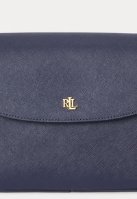 Navy blue structured clutch bag made from textured material, featuring a curved flap and gold-tone logo hardware at the center.