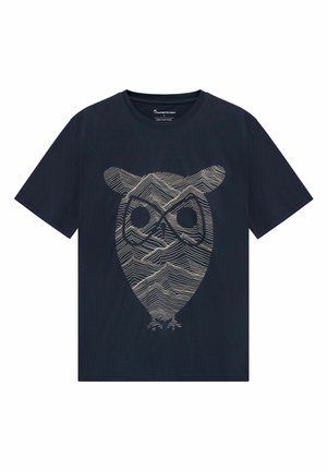 Marineblauw T-shirt met beige lijnkunst die een abstracte uilengezicht vormt, samengesteld uit golvende, bergachtige patronen.