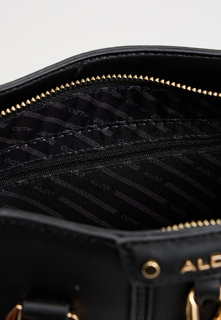 Interno della borsa nera con texture liscia, zip dorata e una tasca con cerniera. Rivestita in tessuto nero con un delicato motivo a logo.