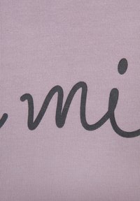 Helles rosa Gewebe mit gerippter Textur, das in kräftiger schwarzer Schreibschrift den Schriftzug "mi." zeigt. Das Design ist einfach und modern und hebt die Typografie hervor.