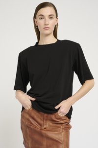 T-shirt nera a maniche corte con una vestibilità relax e scollo rotondo, abbinata a una gonna di pelle marrone con tasche frontali e una texture liscia.