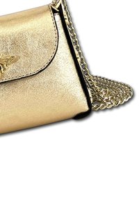 Gouden metallic schoudertas met een klep sluiting, voorzien van een kettingriem en zwarte afwerking, met een gladde textuur en subtiele glans.