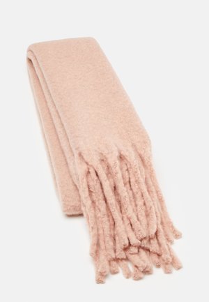 Écharpe en laine douce rose pâle pliée avec de longues franges à une extrémité sur un fond blanc uni.