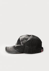 Svart denim-lue med buet brem, slitte kanter og logo-detall på siden. Har et klassisk seks-paneldesign og stofftextur.