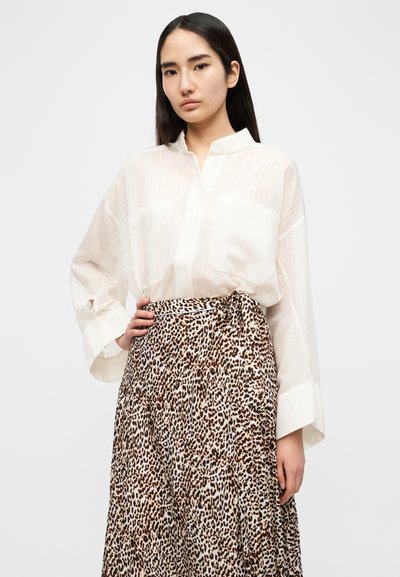 Λευκό, ημιδιάφανο πουκάμισο με κάθετες ρίγες, γιακά και μακριά μανίκια, σε συνδυασμό με μακριά φούστα animal print λεοπάρ με δέσιμο στη μέση.
