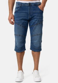 Shorts din denim de culoare albastră cu cusături contrastante, talie ajustabilă și detalii unice de panouri pe lungimea picioarelor.