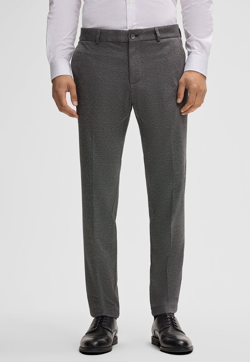 Pantalons gris texturés à coupe slim, dotés d'une taille et d'une fermeture à bouton. Assortis à des chaussures de ville noires.