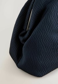Sötétkék, texturált szövet táska, pliszírozott dizájnnal, sima fémes kiegészítővel. A felületen egy jellegzetes, szőtt minta látható.