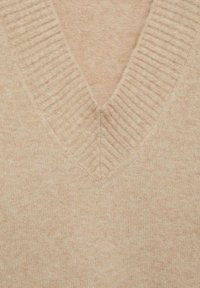 Tissu tricoté beige doux avec un large col en V côtelé, montrant une texture détaillée et des fibres fines de laine.