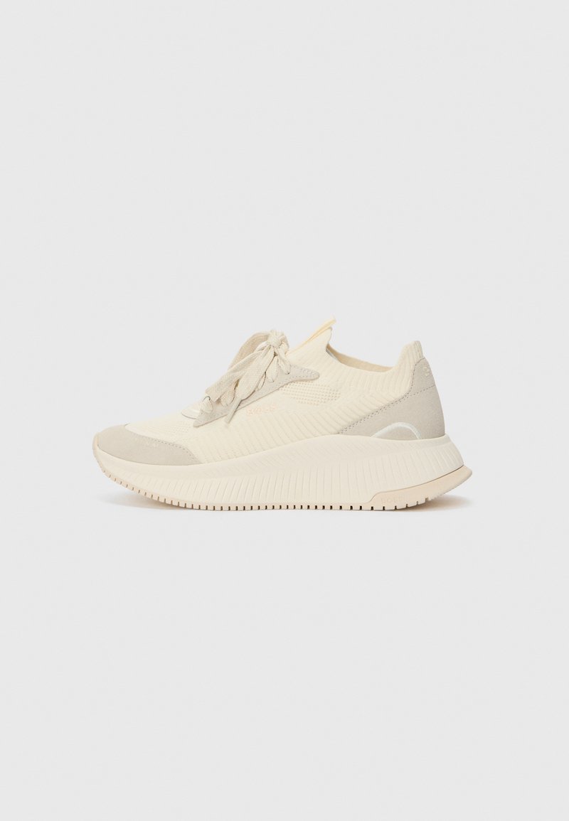 Beige sportsko med en tekstureret strikoverdel, kontrasterende suede detaljer og en gummisål med riller for bedre greb.