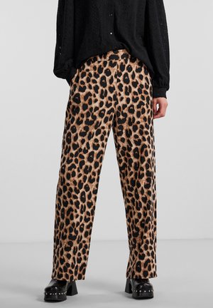 Pantalon à jambes larges imprimé léopard en tissu beige et noir, avec une texture lisse. Associé à un chemisier noir ample à manches longues.