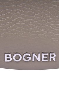 Szara skórzana powierzchnia z teksturowanym wzorem i wyraźnym białym logo "BOGNER" w eleganckiej, nowoczesnej czcionce.