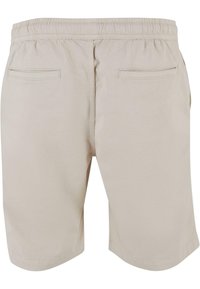 Beige rövidnadrág állítható derékkal, két hátsó zsebbel és sima, könnyű anyagból készült. Az alján kifordított széllel.