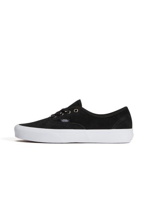 Sneaker Vans nera dal profilo basso con suola in gomma bianca e lacci neri, mostrata di lato su sfondo bianco.