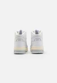 Sneakers alta bianche con una tomaia in pelle testurizzata, suola intermedia color crema e suola esterna in gomma grigia. Presentano un colletto imbottito e dettagli di branding.