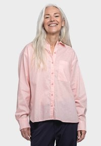 Light pink long-sleeve button-up shirt with a chest pocket and soft texture. Features a rounded hem and slightly oversized fit.