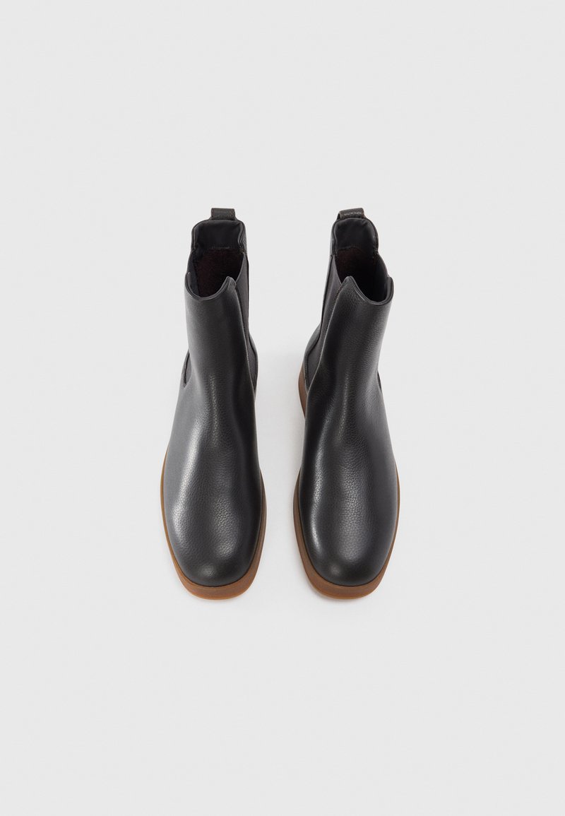 Schwarze Leder-Ankle Boots mit glatter Textur, runder Zehenform und elastischen Seiteneinsätzen. Ausgestattet mit einer braunen Gummisohle. Standardhöhe.