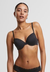 Soutien-gorge rembourré noir avec dentelle, bretelles réglables et texture lisse. Son design simple met l'accent sur le confort et le soutien.
