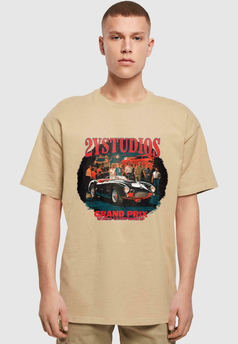 Beige katoenen t-shirt met korte mouwen en een ronde hals, voorzien van een vintage auto graphic in zwart en rood met "2YSTUDIOS" en tekst eronder.