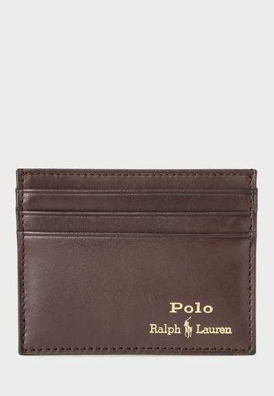 Brown leather cardholder with four card slots, embossed gold logo, and visible stitching details. Smooth texture with a rectangular shape.